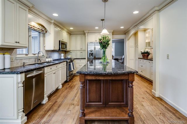 a kitchen with stainless steel appliances granite countertop a sink a stove and a wooden floors