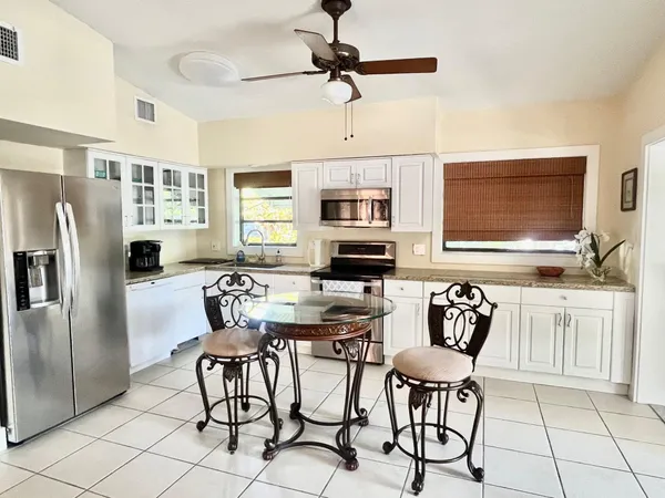 a kitchen with stainless steel appliances granite countertop a dining table chairs refrigerator and microwave
