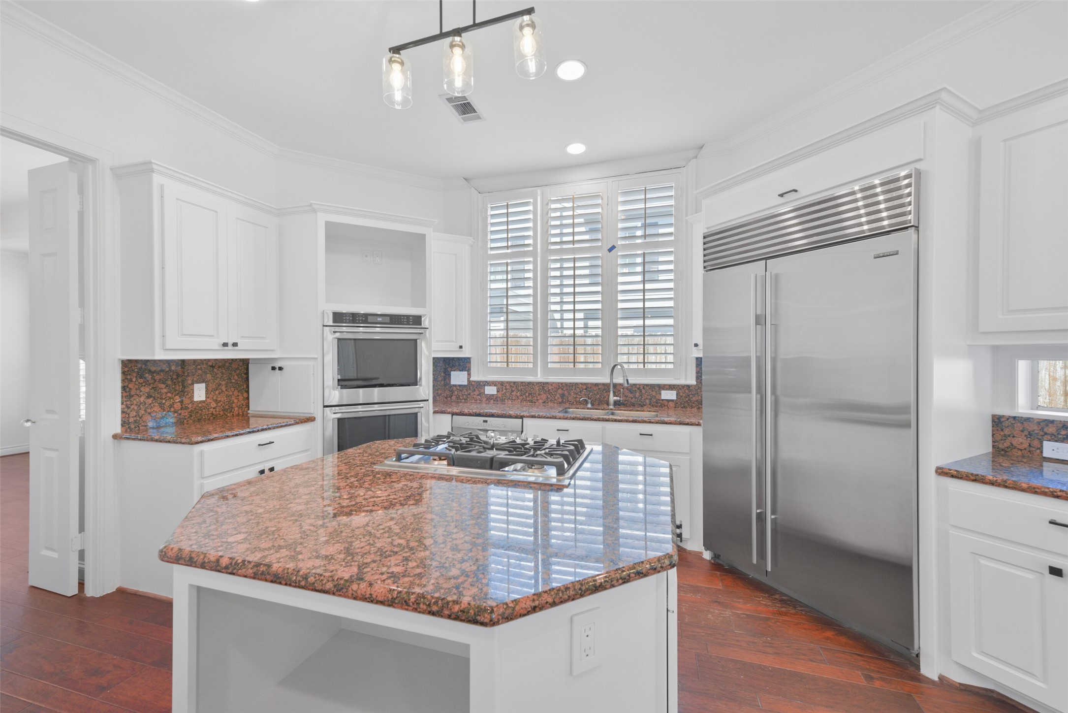 3724 Wroxton Road Houston, TX 77005 - Photo 14 of 40 Center island with cooktop and built-in storage takes center stage. Stainless appliances, including 2015 Subzero and 2021 KitchenAid double ovens.