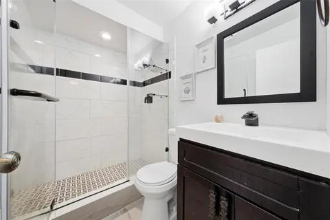a bathroom with a sink a toilet a mirror and shower