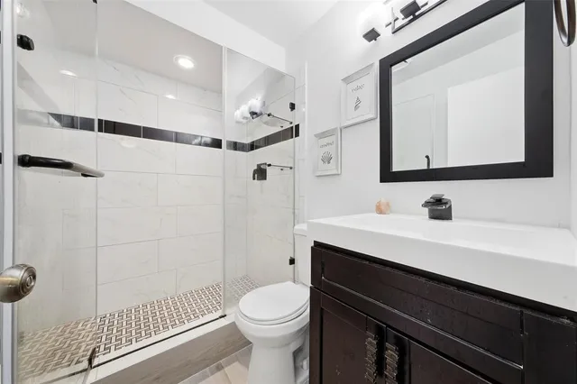 a bathroom with a sink a toilet a mirror and shower