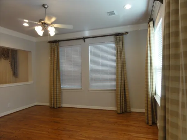 an empty room with wooden floor mirror and windows