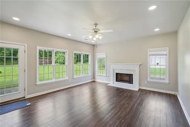 a view of an empty room with wooden floor fireplace and a window