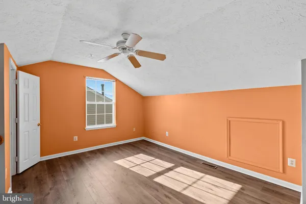 an empty room with wooden floor ceiling fan and windows