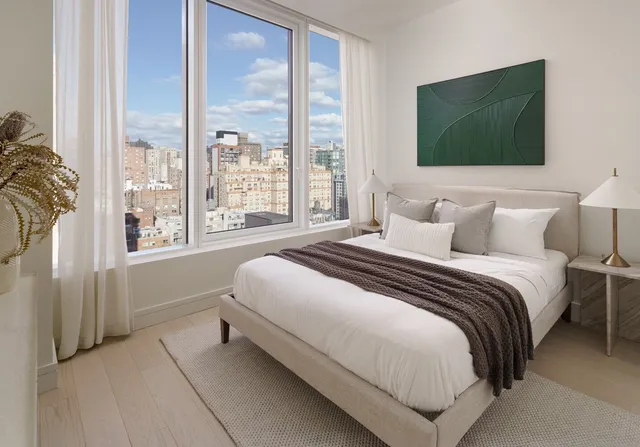 a bedroom with a bed and a flat tv screen next to a window