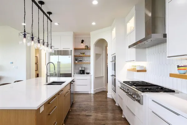 a large kitchen with stainless steel appliances kitchen island granite countertop a table and chairs in it
