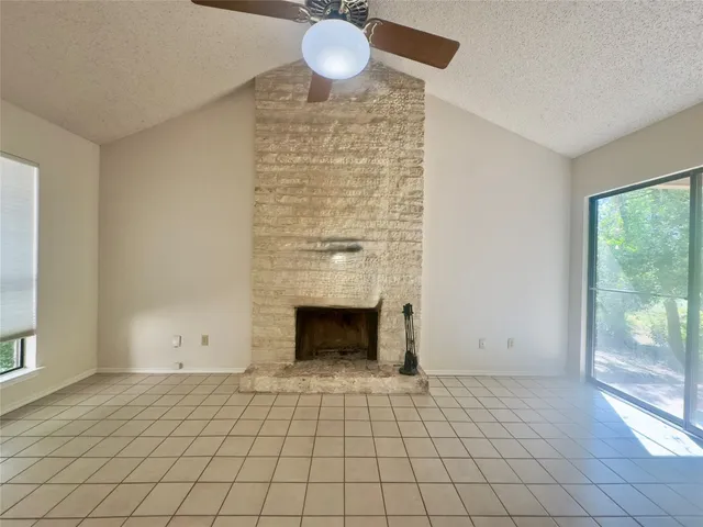 a view of an empty room with window and chandelier fan