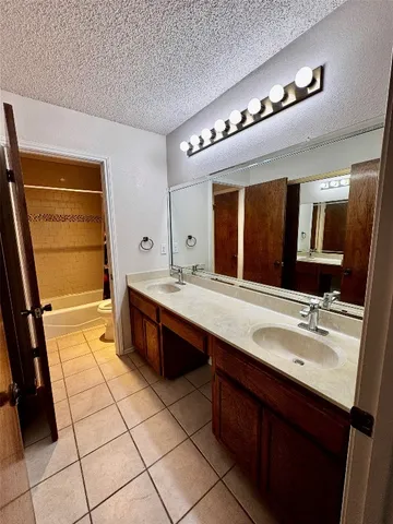 a spacious bathroom with a double vanity sink a mirror and a bathtub