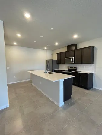 a large kitchen with a large counter top a sink stainless steel appliances and cabinets