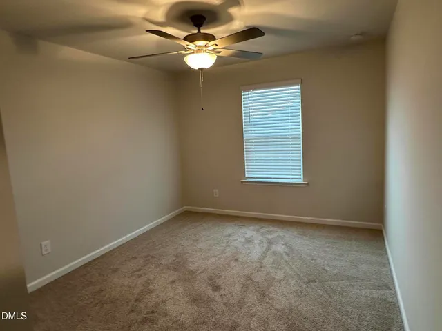 an empty room with a window and a fan