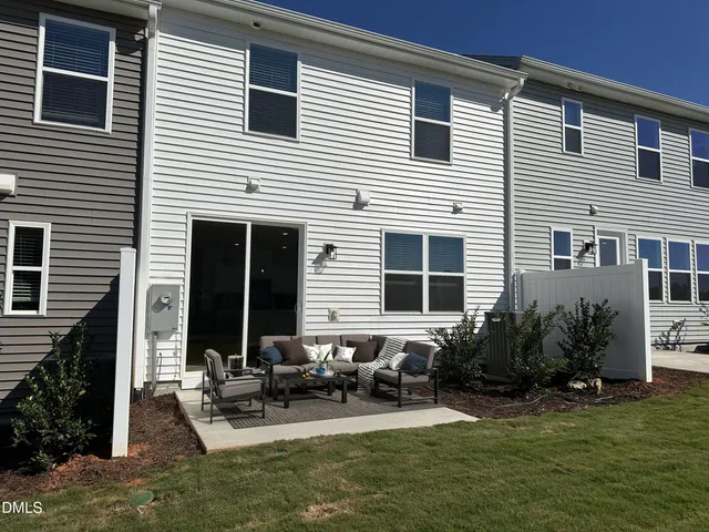 a view of house with back yard and sitting area