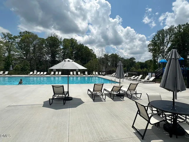 a view of swimming pool with table and chairs under an umbrella
