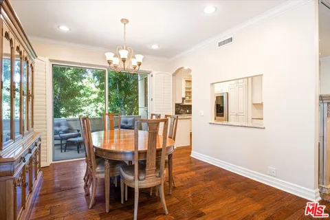 a kitchen with stainless steel appliances granite countertop a refrigerator a stove a sink a dining table and chairs with wooden floor