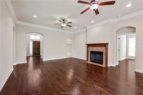 a view of an empty room with wooden floor and a fireplace