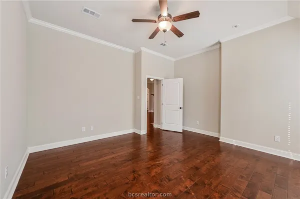 an empty room with wooden floor and ceiling fan