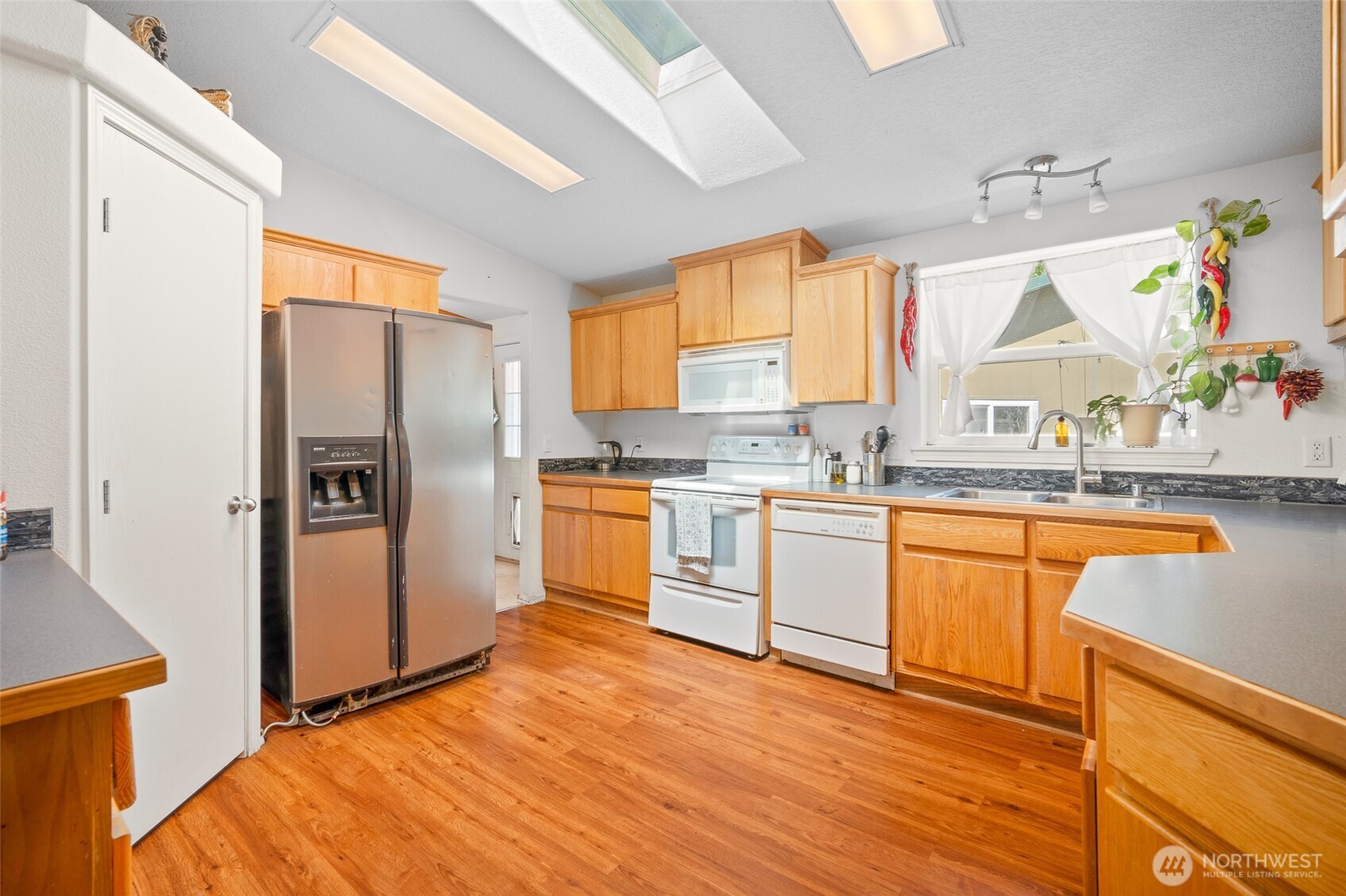 4230 Cody Road Blaine, WA 98230 - Photo 14 of 38 a kitchen with stainless steel appliances granite countertop a refrigerator a sink dishwasher a stove with wooden cabinets and floor
