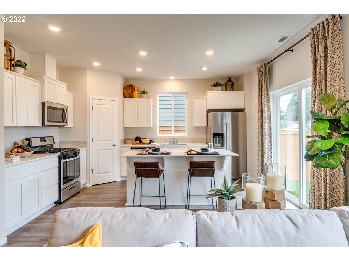 2667 U Street Springfield, OR 97477 - Photo 11 of 30 a kitchen with stainless steel appliances granite countertop a stove top oven a refrigerator a sink and a dining table with wooden floor