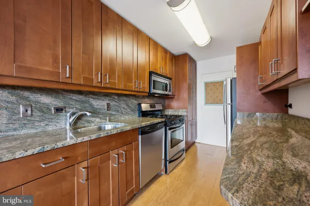 a kitchen with granite countertop wooden cabinets stainless steel appliances and a sink