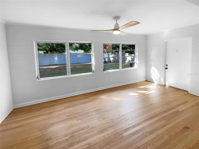 an empty room with wooden floor and windows