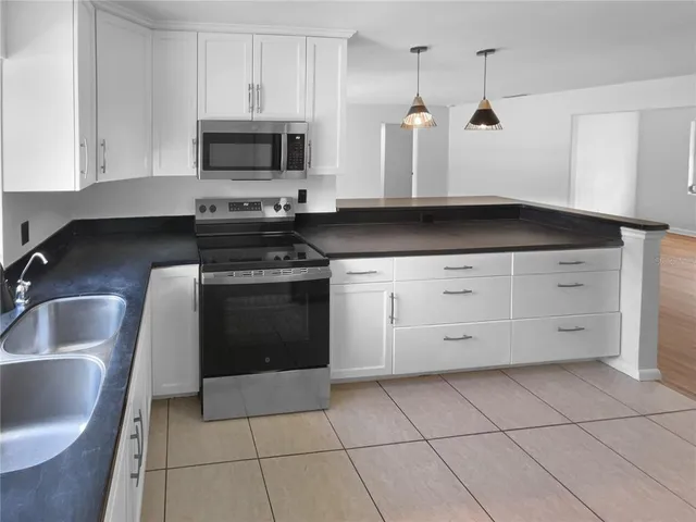 a kitchen with granite countertop a stove a sink and a microwave