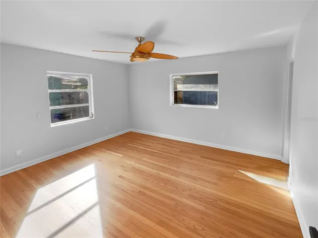 a view of an empty room with wooden floor and a window