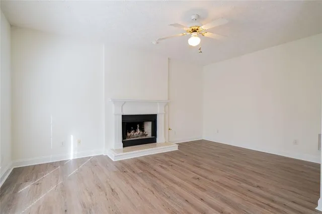 a view of an empty room with wooden floor a fireplace