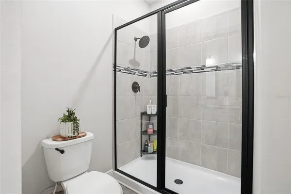 a bathroom with a shower a toilet and a window