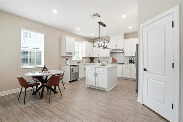 a kitchen with stainless steel appliances kitchen island granite countertop a table chairs and a refrigerator