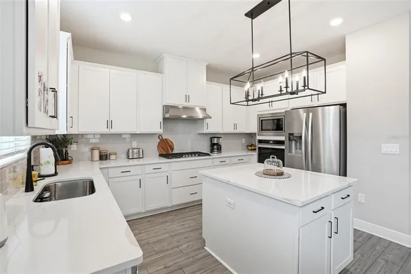 a kitchen with stainless steel appliances granite countertop a sink stove and refrigerator