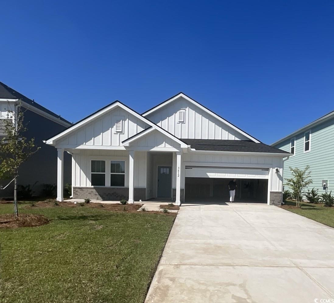 View of front of house featuring board and batten siding, a front lawn, driveway, and a garage