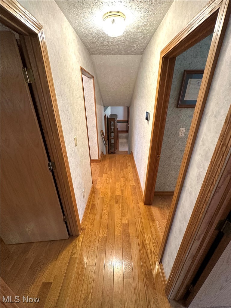 1684 Morris Street Mineral Ridge, OH 44440 - Photo 34 of 50 Hallway featuring a textured ceiling, light wood-type flooring, lofted ceiling, and a textured wall