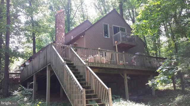 a view of house with wooden stairs and a small yard in front of it