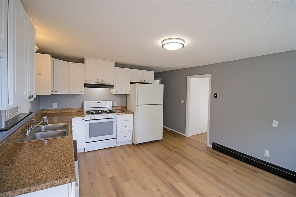 45 Depot Street, Unit 2 Sharon, MA 02067 - Photo 5 of 12 a kitchen with granite countertop a refrigerator and a stove top oven