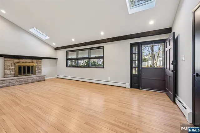 an empty room with wooden floor fireplace and windows