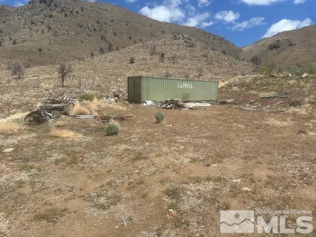 a view of a dry yard with mountains in the background
