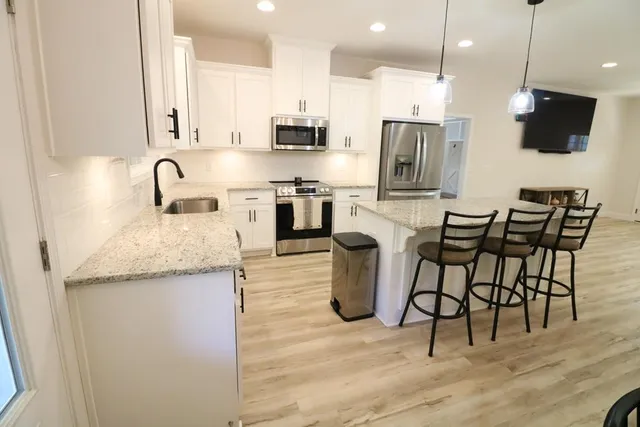 a kitchen with stainless steel appliances granite countertop a stove top oven a sink a microwave and a refrigerator