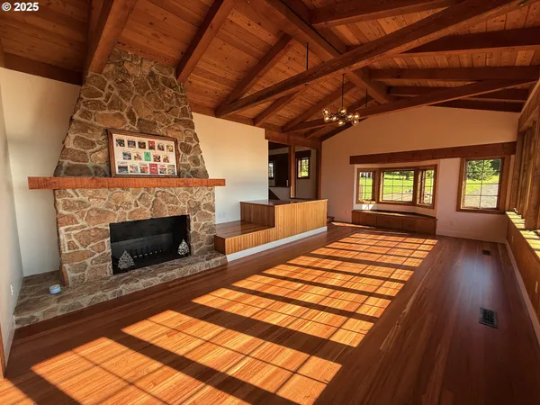 a view of an empty room with wooden floor fireplace and a window