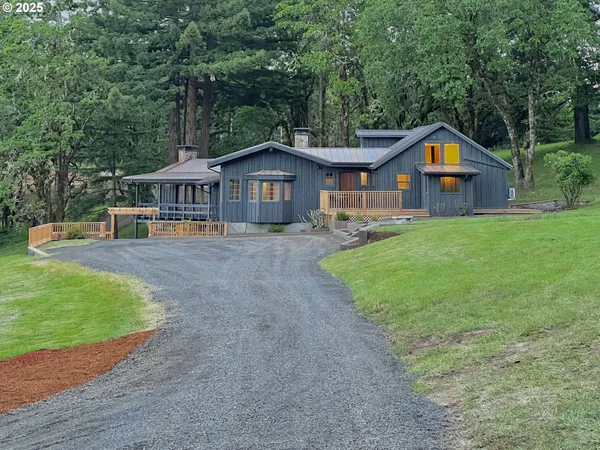 a view of a house with a yard and large trees