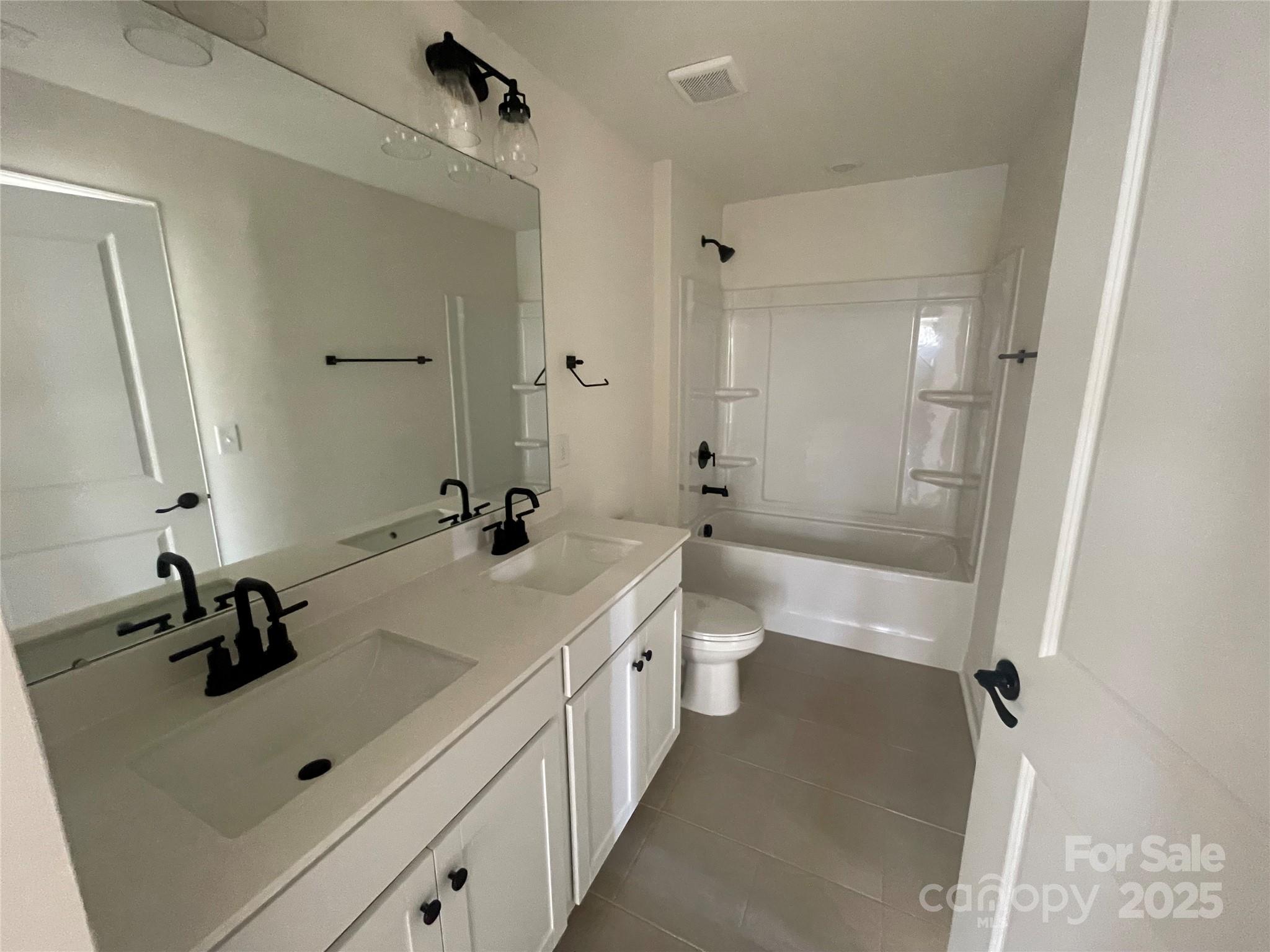 4044 Grommet Court Matthews, NC 28105 - Photo 14 of 27 a bathroom with a double vanity sink a mirror and a bathtub