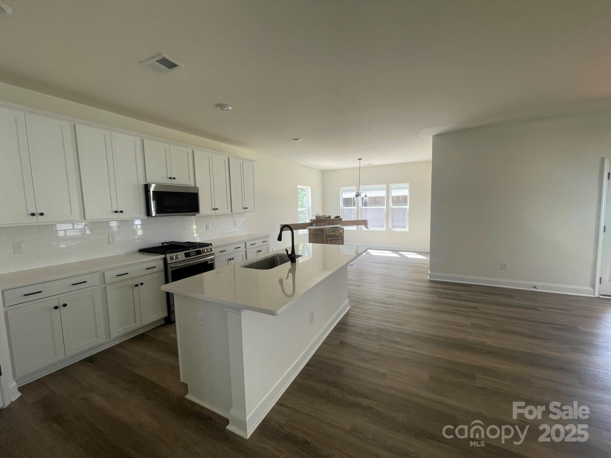 4044 Grommet Court Matthews, NC 28105 - Photo 17 of 27 a large white kitchen with a stove a sink and dishwasher with wooden floor