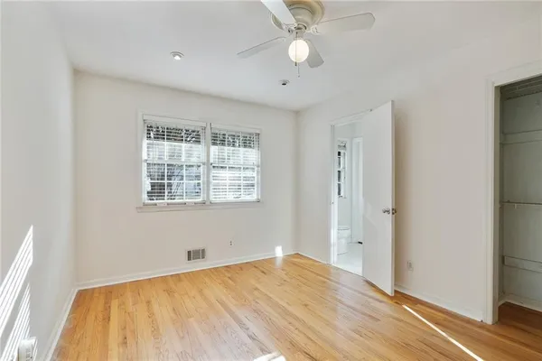a view of empty room with wooden floor and fan