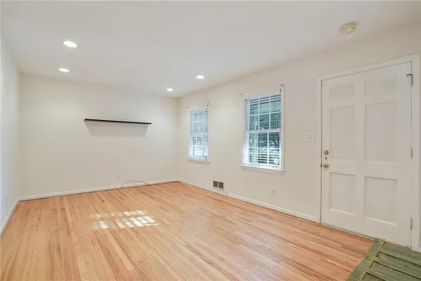 a view of an empty room with wooden floor and a window