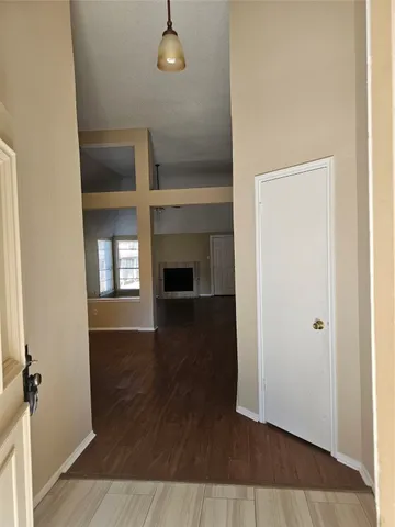 an empty room with wooden floor fireplace and windows