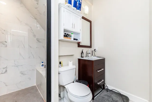 a bathroom with a toilet sink vanity granite and shower