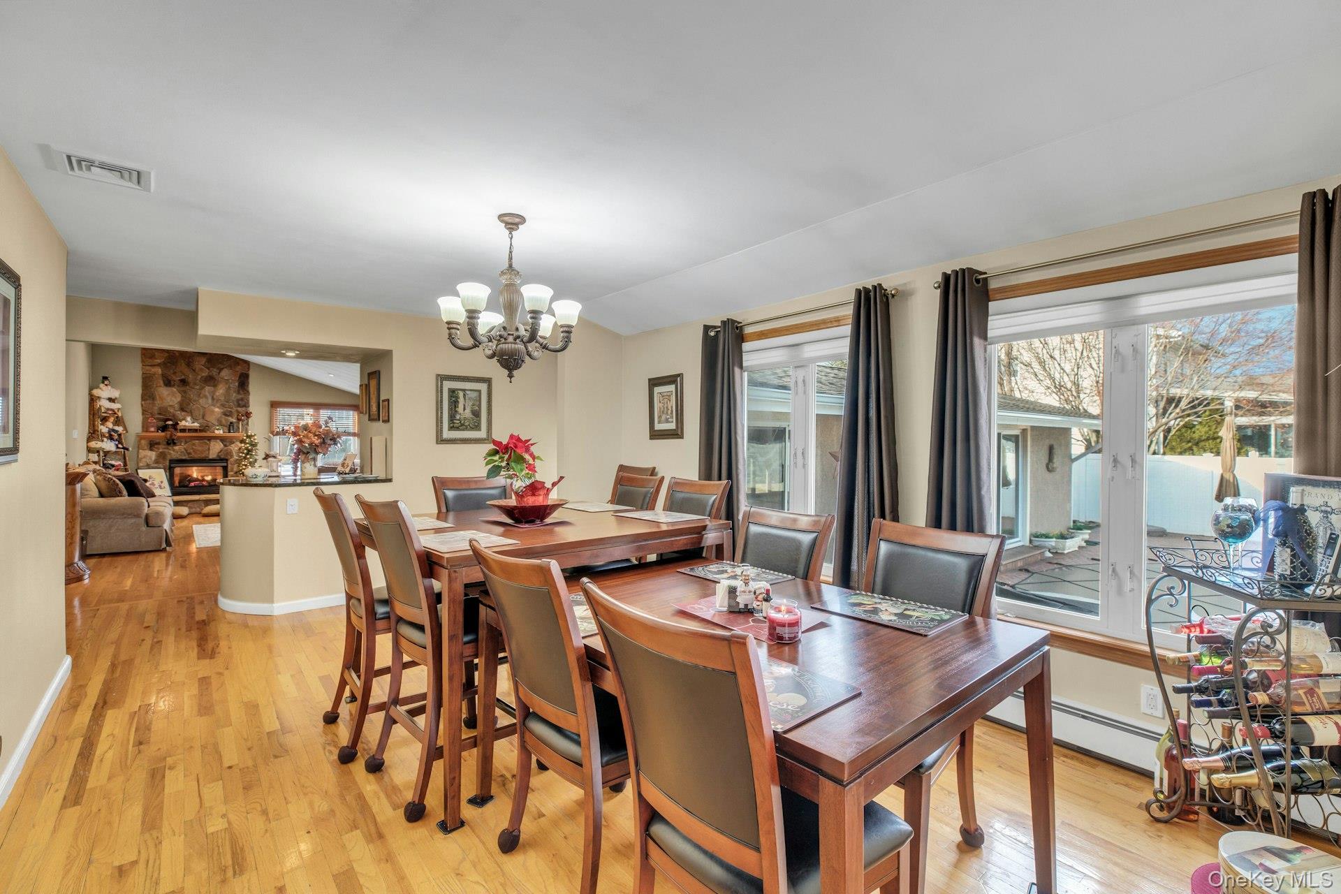 1044 Commack Road Dix Hills, NY 11746 - Photo 14 of 29 Dining area with a stone fireplace, a chandelier, light wood finished floors, and baseboard heating
