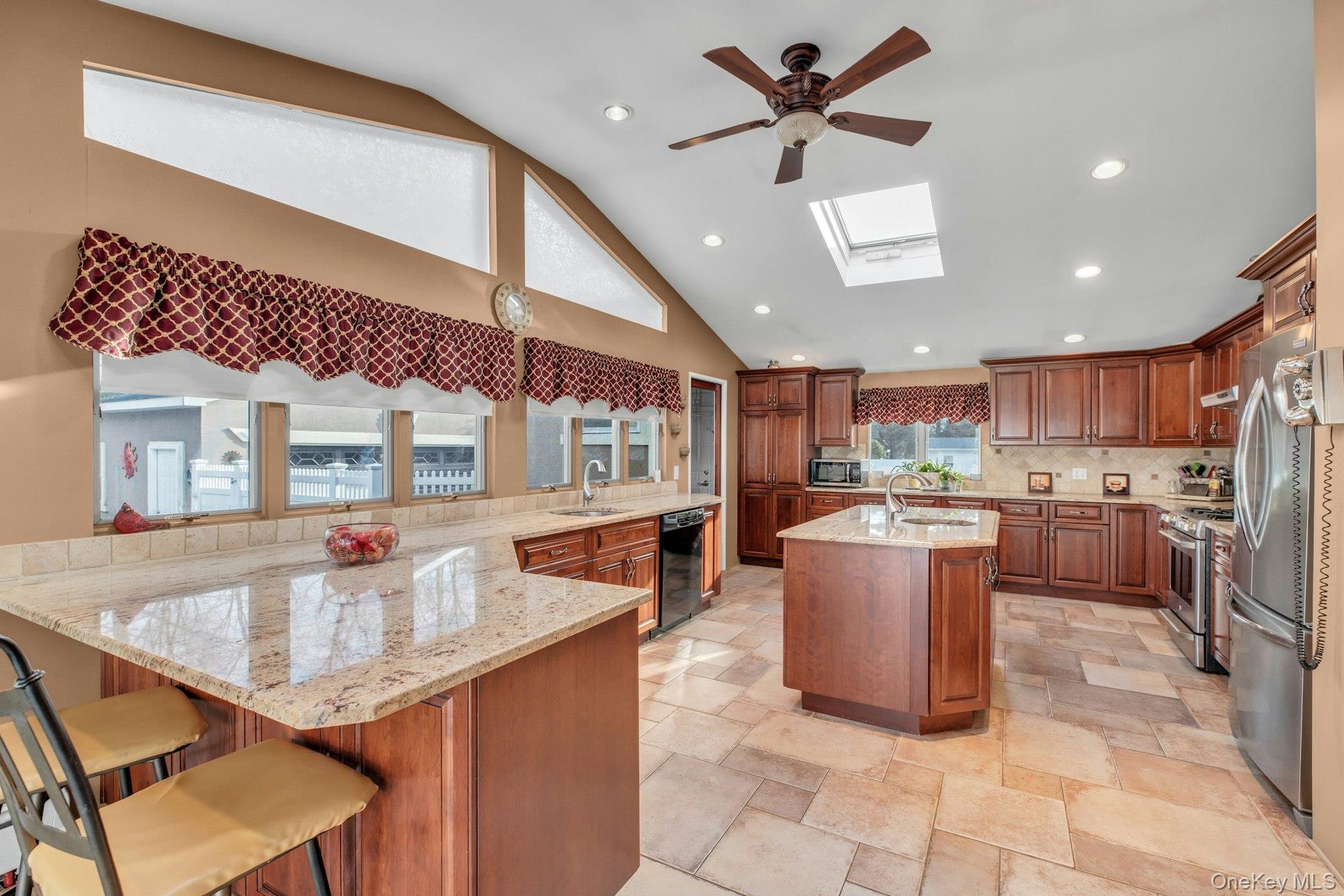 1044 Commack Road Dix Hills, NY 11746 - Photo 15 of 29 Kitchen featuring a peninsula, a skylight, recessed lighting, stainless steel appliances, and light stone counters
