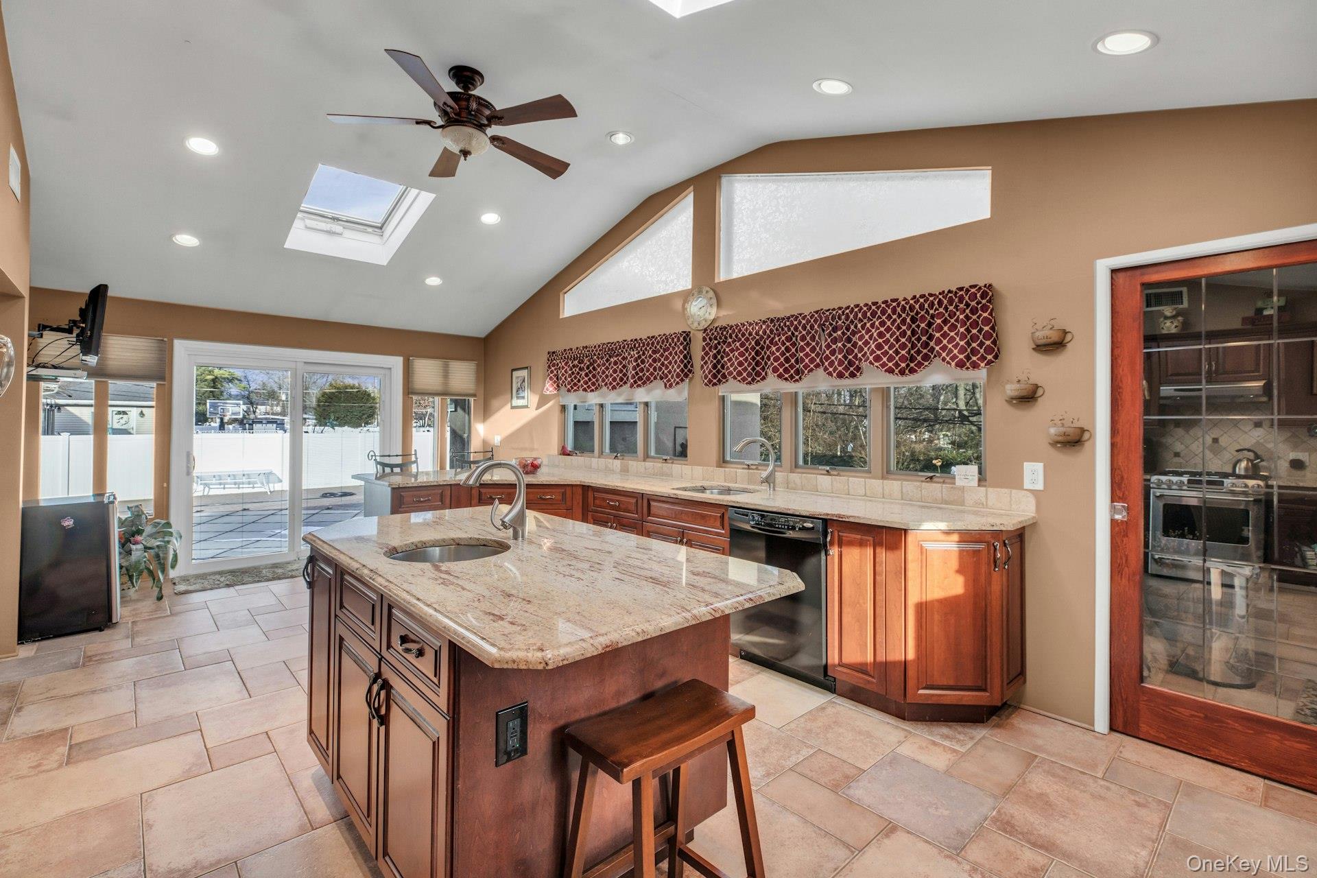 1044 Commack Road Dix Hills, NY 11746 - Photo 18 of 29 Kitchen with light stone counters, high vaulted ceiling, brown cabinets, gas range, and black dishwasher