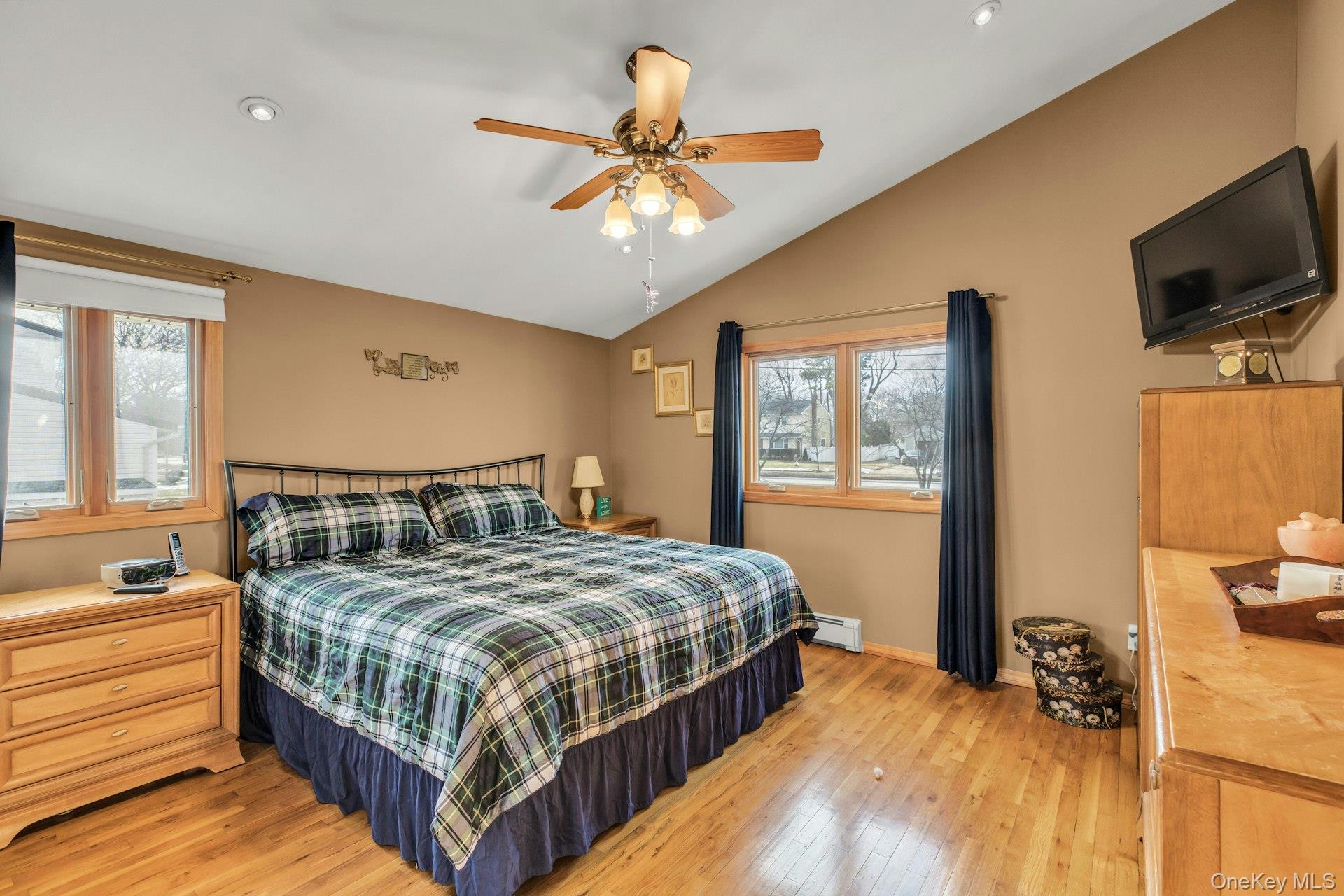 1044 Commack Road Dix Hills, NY 11746 - Photo 21 of 29 Bedroom with light wood-type flooring, vaulted ceiling, ceiling fan, a baseboard radiator, and recessed lighting