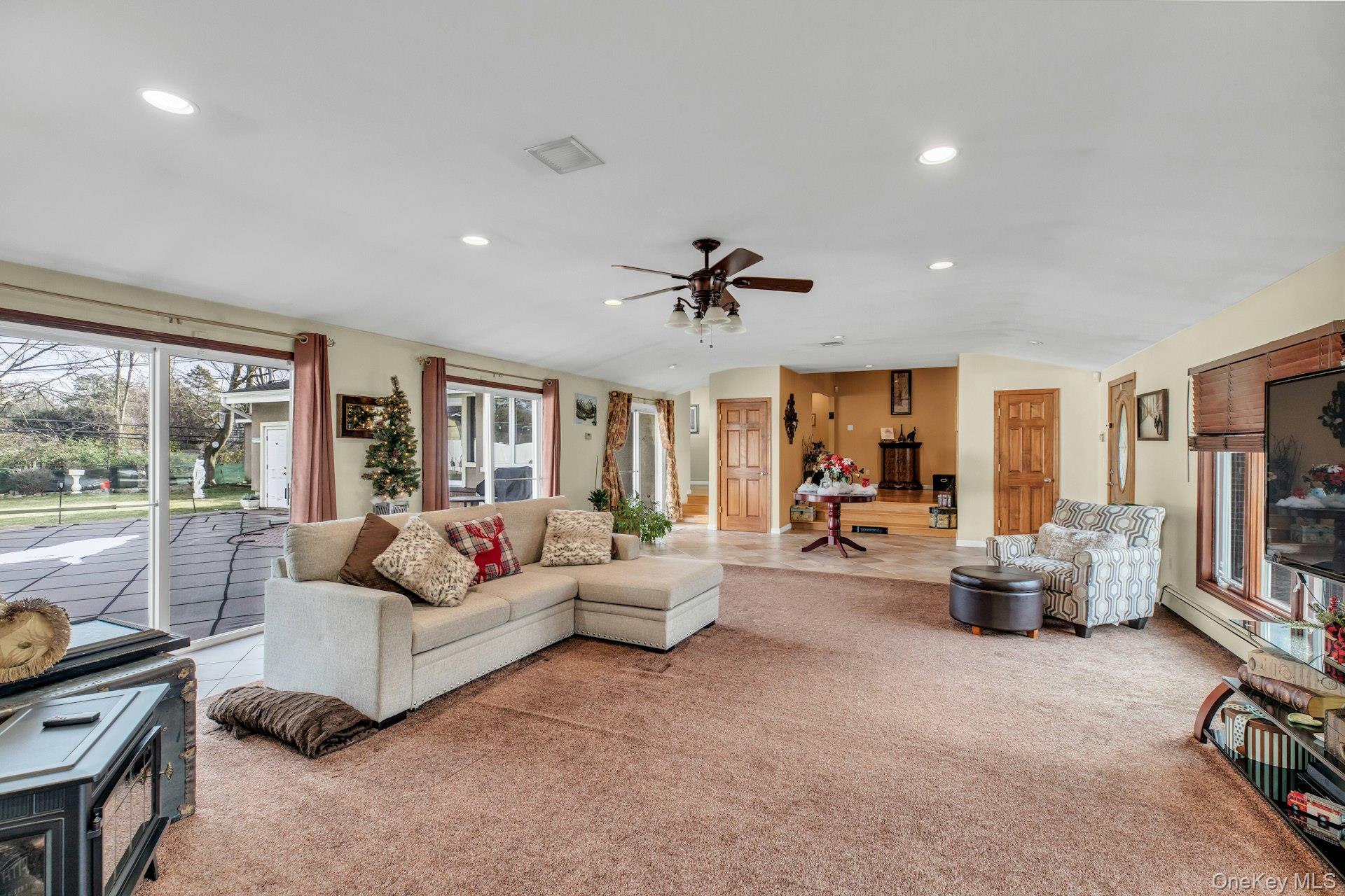 1044 Commack Road Dix Hills, NY 11746 - Photo 7 of 29 Carpeted living room featuring a ceiling fan, lofted ceiling, a baseboard radiator, and recessed lighting