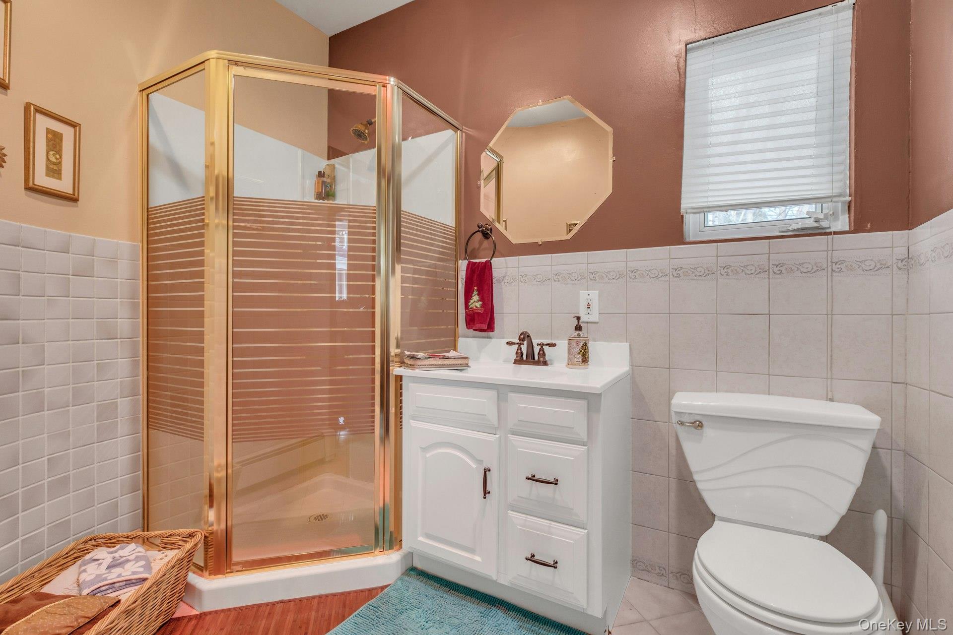 1044 Commack Road Dix Hills, NY 11746 - Photo 8 of 29 Bathroom featuring a shower stall, vanity, tile walls, wainscoting, and light tile patterned floors